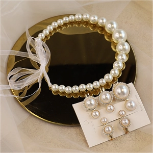 Detail of white pearl jewelry set with ribbon necklace and gold crystal earrings