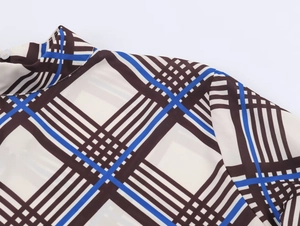 Detail of high collar plaid blouse with beige, brown and blue patterns and button close