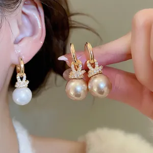 Boucles d'oreilles perles plaquées or avec zircons portées par un mannequin et à la main