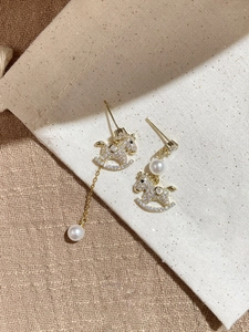 Detailed macro shot of gold-plated pony earrings with pavé crystals and white pearls