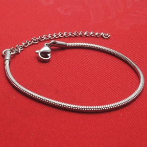Adjustable silver titanium snake chain bracelet with lobster clasp on red background