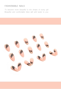 Macro shot of almond-shaped press-on nails with black leaf patterns and gold foil flakes