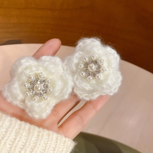 Détail de pinces à fleurs tricotées main avec perles centrales et cristaux