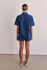 Rear view of women's dark blue denim set featuring short sleeve shirt and folded hem shorts