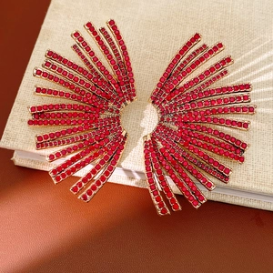 Macro detail of gold fan-shaped stud earrings with sparkling red rhinestone inlay