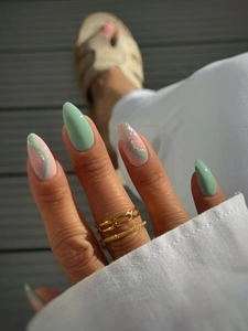 Close-up of mint green and nude pink almond press-on nails with silver glitter details
