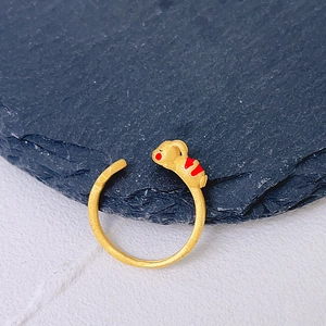 Macro shot of gold adjustable ring featuring a cute red-accented mouse on a stone coaster