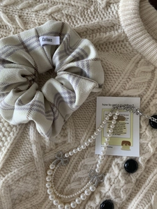 Détail du collier de perles double épaisseur avec pendentifs nœuds et chouchou à carreaux