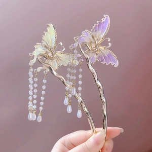 Close-up of golden butterfly hair pins with purple green crystals and pearl tassels