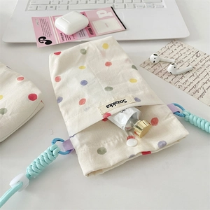 Detailed view of cream fabric mini bag with colorful polka dots and blue braided strap
