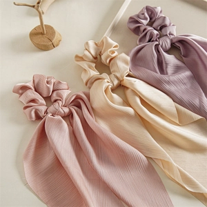 Three elegant nylon hair scrunchies with long ribbons in pastel pink, beige, and purple