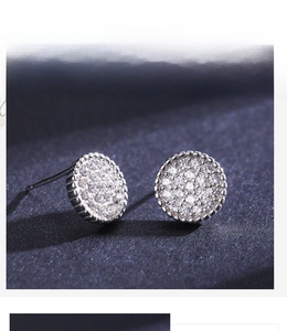 Macro shot of silver stud earrings featuring micro-pave zirconia on a blue background