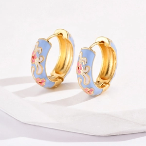 Detail of flower enamel earrings with light blue finish on gold hoops for women
