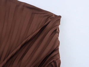 Close-up of dark brown pleated satin fabric detail on a professional通勤 style midi dress
