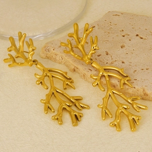 Macro view of gold-plated coral branch drop earrings on natural stone background