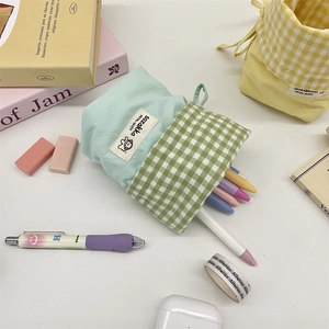 Vertical canvas pencil case with mint green pattern shown standing on a desk with stationery