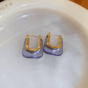 Detail of vintage U-shaped earrings featuring gold hammered metal and purple resin inlay