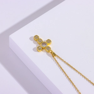 Detailed view of a gold cross pendant necklace with sparkling cubic zirconia inlays