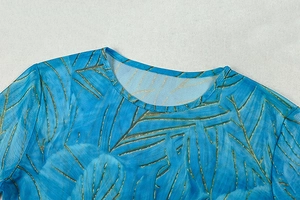 Close-up of blue tropical leaf print on mesh fabric with a round neckline detail