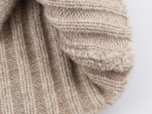 Macro texture showing ribbed knit detail of a light beige soft wool blend sweater