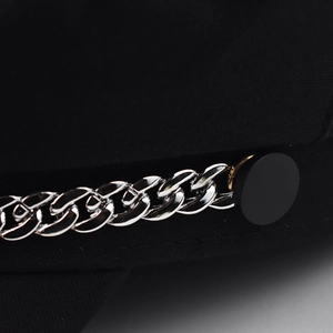 Close-up of silver chain detail and matte buttons on a black wool baker boy hat