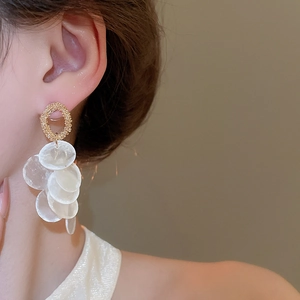 Detail of round shell tassel earrings with gold metal accents and white sequins