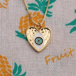 Gros plan détaillé d'un pendentif cœur avec œil porte-bonheur sur collier doré à mailles