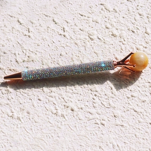 Macro shot of colorful rhinestones on a rose gold metal decorative ballpoint pen
