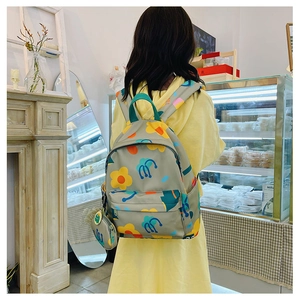 Girl wearing a light grey floral backpack with a matching coin purse in a cozy cafe