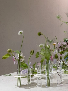 Macro detail of clear glass test tube vases held by white acrylic minimalist holders