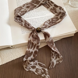Detailed view of leopard print chiffon ribbon with brown bead on vintage book backdrop
