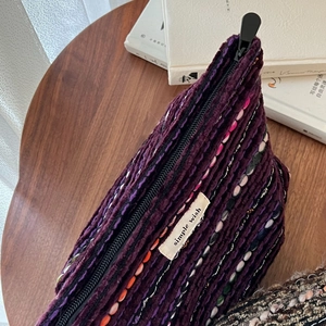 Macro shot of purple woven tweed makeup bag featuring wool texture and a zipper