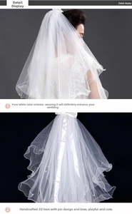 Close-up of white bridal veil featuring pearl accents and a delicate ribbon bow design
