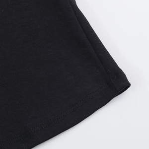 Vista macro dettagliata delle cuciture doppie sull'orlo di una t-shirt nera con perle