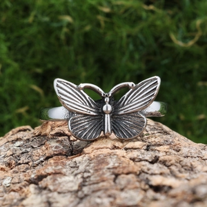 Vintage silver 3D butterfly ring with oxidized metal texture on rustic wood background