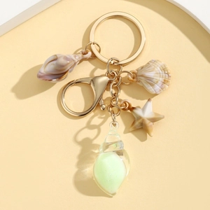 Detail of nautical keychain with golden sea shell, starfish and glowing conch charms
