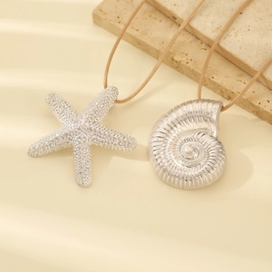Detail of silver starfish and seashell pendants on brown cords with beach vibe aesthetic