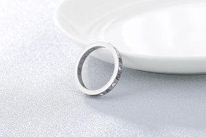 Détail d'une bague argentée avec chiffres romains et cristaux sur une céramique