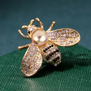 Macro shot of bee brooch with inlaid rhinestones and a large lustrous gold pearl