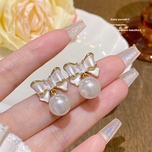 Close-up of elegant 925 silver needle pearl bow earrings with sparkling zircons