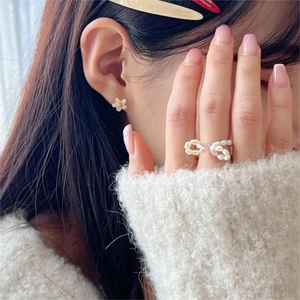 Baroque freshwater pearl bow ring and white flower stud earrings worn by a model