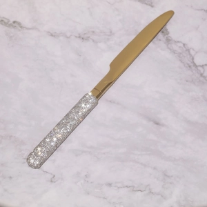 Detailed macro of a gold butter knife featuring a sparkling silver rhinestone handle