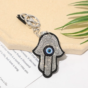 Macro detail of Hamsa Hand keychain with rhinestones and blue Evil Eye charm