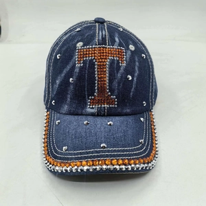 Detailed close-up of blue washed denim baseball cap with rhinestone letter T and metal studs