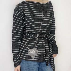 Detailed view of silver heart-shaped rhinestone crossbody bag on a striped outfit