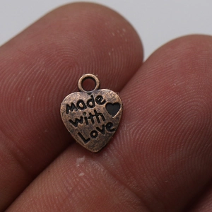 Vista macro de un pequeño colgante de corazón de bronce vintage grabado Made with Love