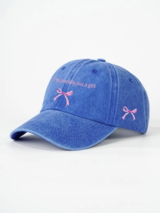 Close-up of pink I'm literally just a girl embroidery and bow on navy denim cap