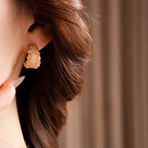 Gros plan de boucles d'oreilles en C plaquées or serties de zircones sur un mannequin