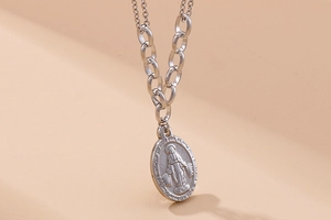 Detail of silver oval religious pendant with saint icon on chunky chain link necklace