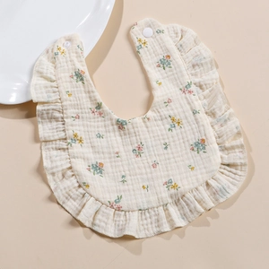 Detailed macro view of 4-layer muslin cotton baby bib with floral print and ruffle edges
